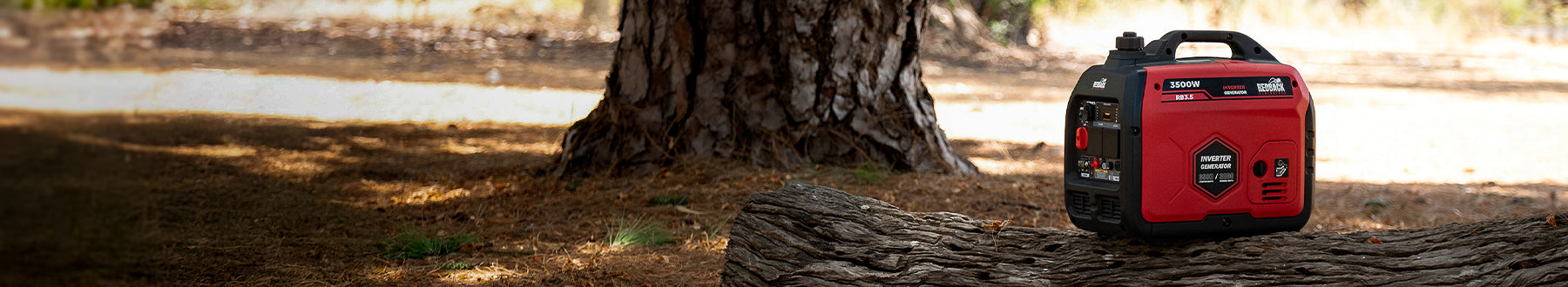 A small red and black portable generator sits on a large tree trunk in a wooded outdoor area with sunlight filtering through the trees.
