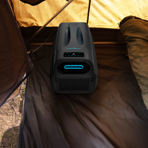 The iTechworld iFROST Portable Air Conditioner (1000W/3412BTU) sits on a tent floor, its blue LED control panel glowing, delivering cool comfort for outdoor adventures beside brown tent walls and a sleeping bag.