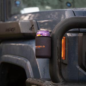An iTechworld Magnetic Stubby Holder (375mL) in black holds a purple soda can, attached to the front grill guard of a blue off-road vehicle with water droplets visible on the metal.