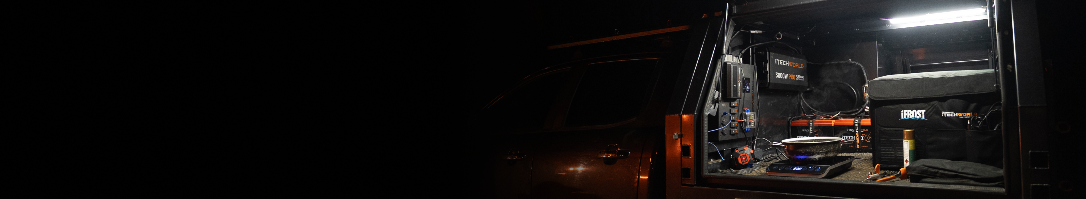 A close-up of the back of a vehicle fitted with Tech World lithium batteries and power equipment, parked outdoors near trees.