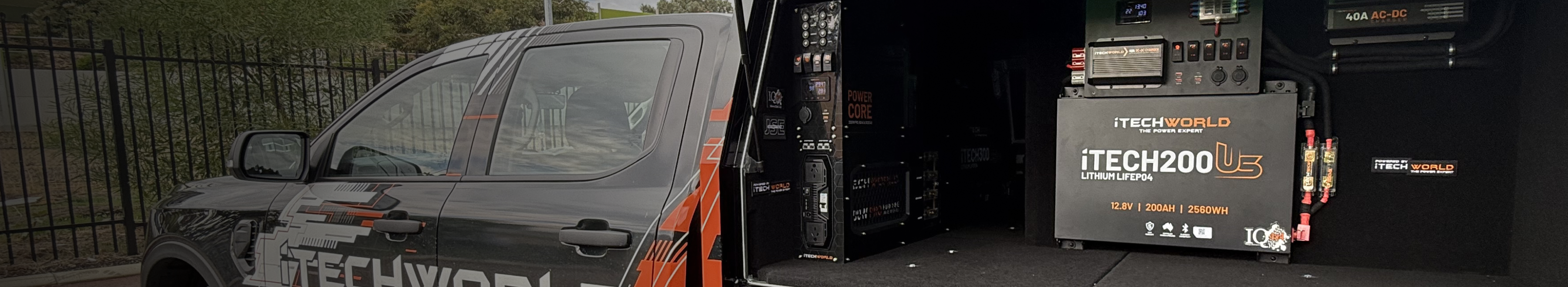 A branded vehicle with ITECHWORLD logo is parked next to open storage containing large lithium battery units. Bold orange text reads BATTERY SEASON with a lightning bolt.