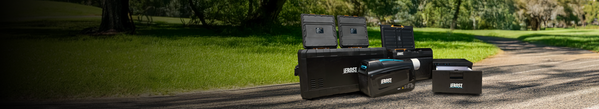 Three iFROST portable refrigerators with open lids, set on a path in a park.