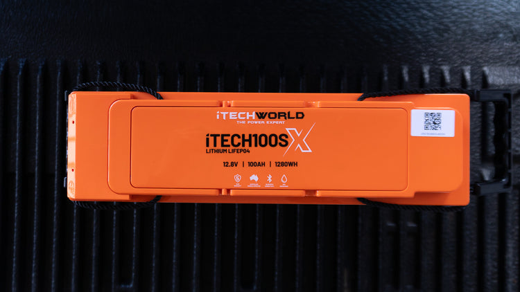 The iTechworld iTECH100SX Slim Deep Cycle Lithium Battery, 12.8V 100Ah Bluetooth LiFePO4, is ultra-lightweight; shown from above on a black textured surface.