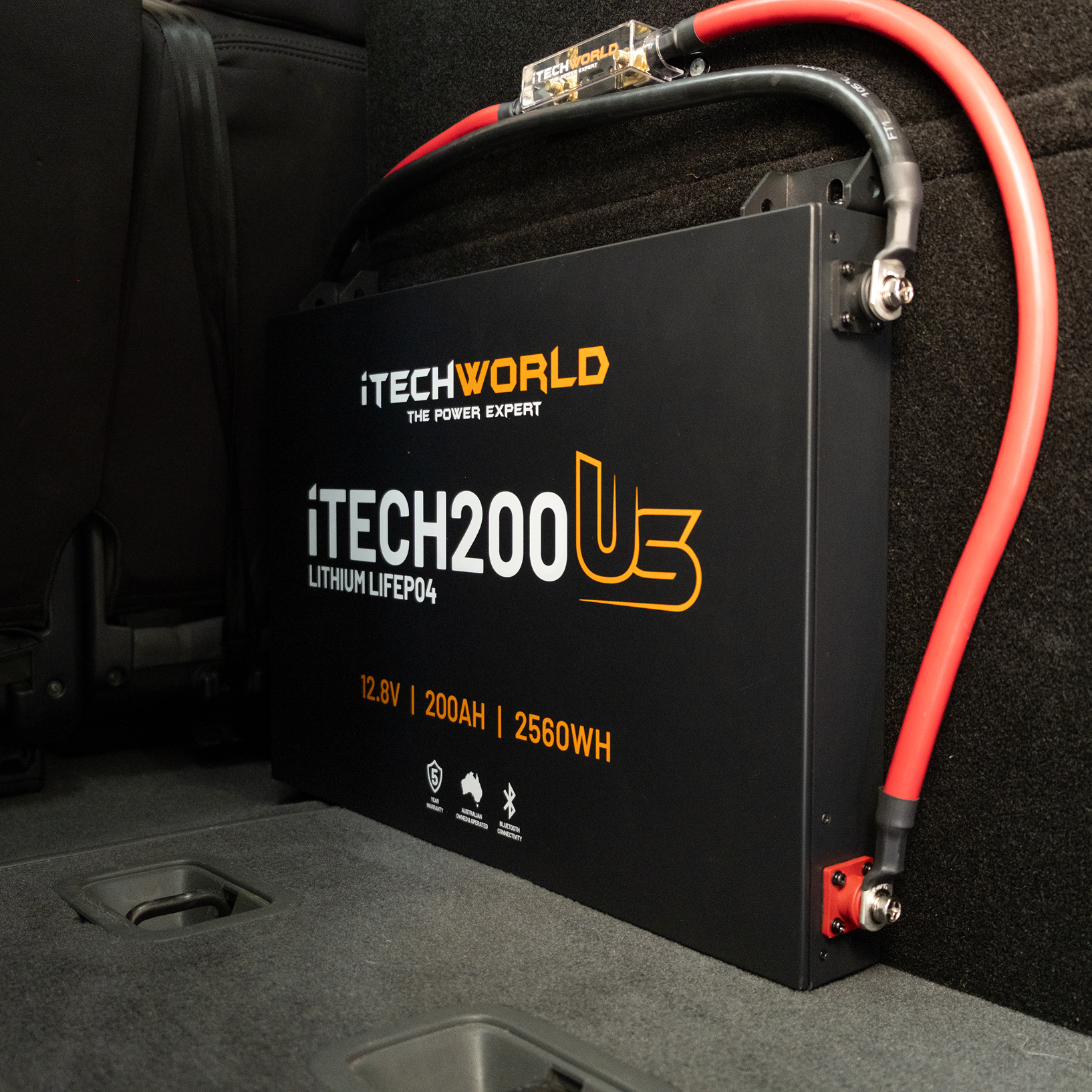 An iTechworld iTECH200US Ultra Slim Deep Cycle Lithium Battery (12.8V, 200Ah, 2560Wh) with Bluetooth and red/black cables is installed in the vehicle's rear compartment.