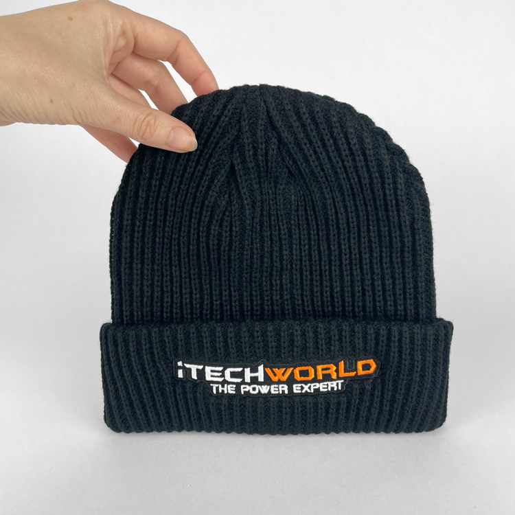 A hand holds the iTechworld Black Beanie—an insulating, cold-weather essential—featuring "ITECHWORLD THE POWER EXPERT" embroidered in white and orange. The ribbed beanie is shown against a plain white background.