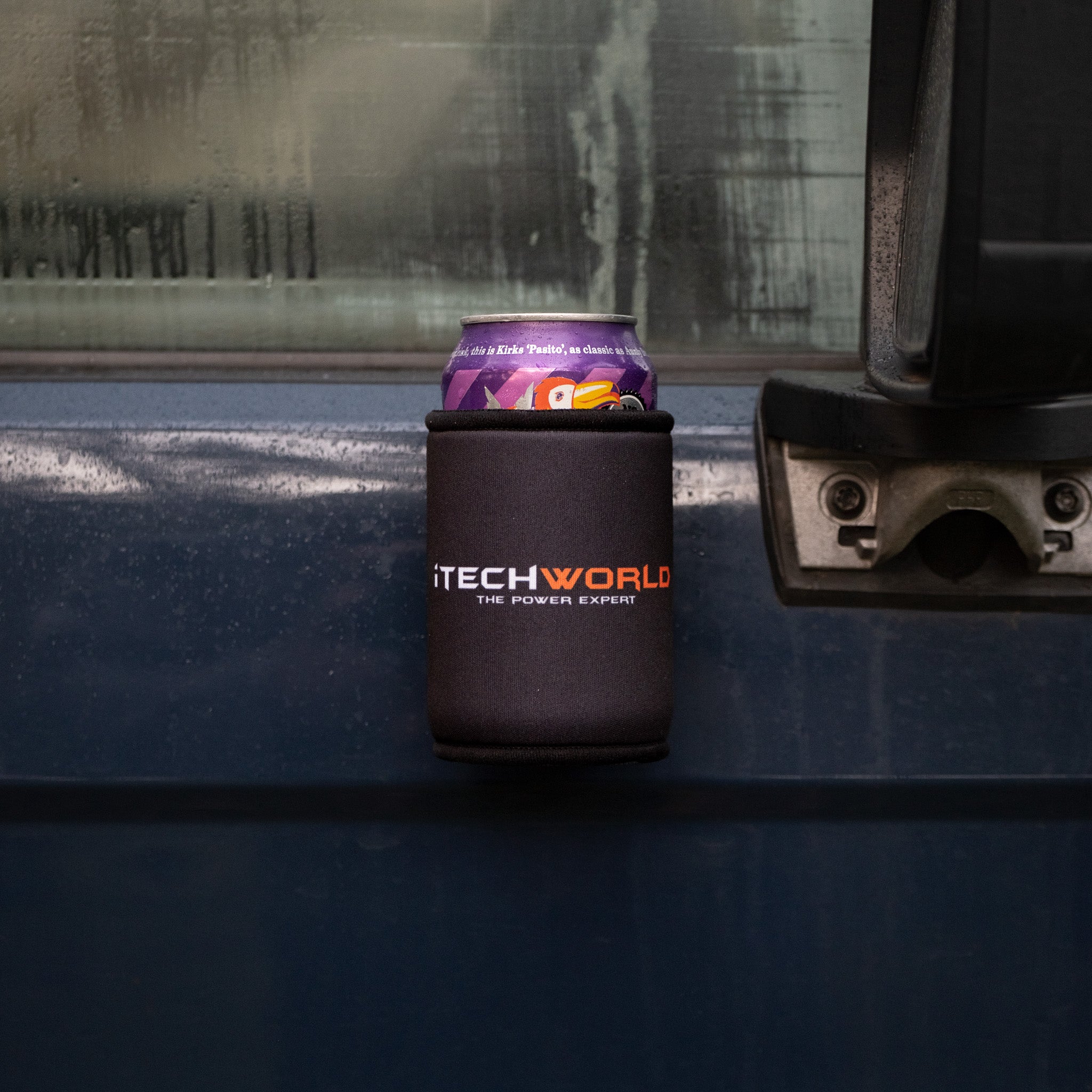 A 375mL can sits in an iTechworld Magnetic Stubby Holder, attached to the outside of a blue vehicle’s door near the handle, with condensation visible on the window.