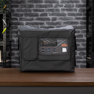 An iTechworld portable power station is positioned on a wooden table in front of a gray brick wall and black metal shelves, safeguarded by the iTechworld Power Station Cover PS2000 for enhanced durability.