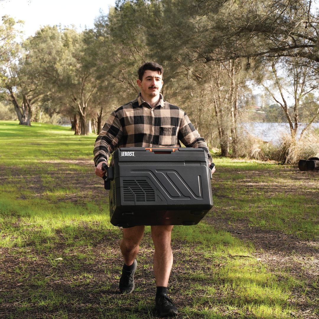 A young man carrying the iFROST 40L portable fridge freezer