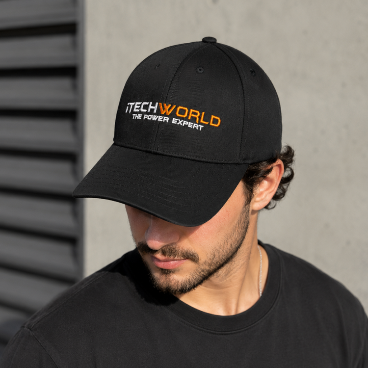 A man in an iTechworld embroidered black hat, made from breathable cotton for comfort, stands against a gray wall and looks down to his left.