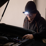 A man uses the iTechworld Magnetic Head Torch 450LM to examine a car engine.