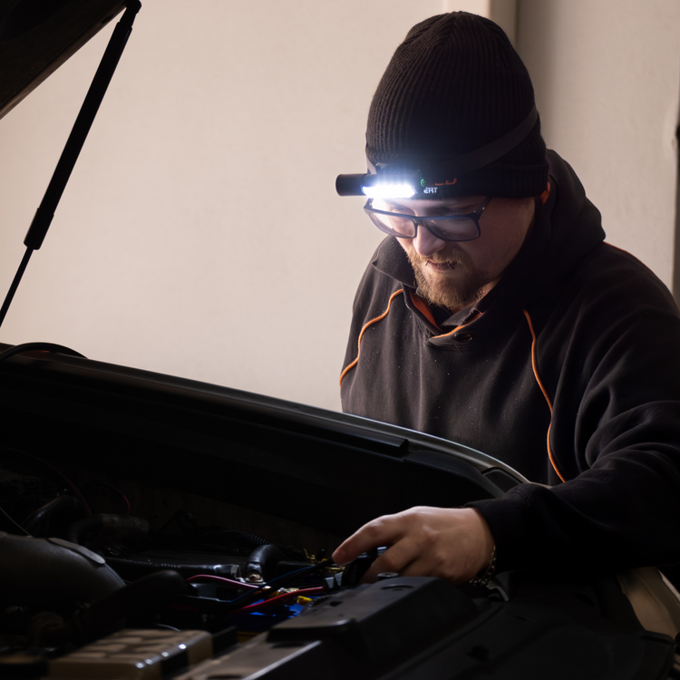 A man uses the iTechworld Magnetic Head Torch 450LM to examine a car engine.