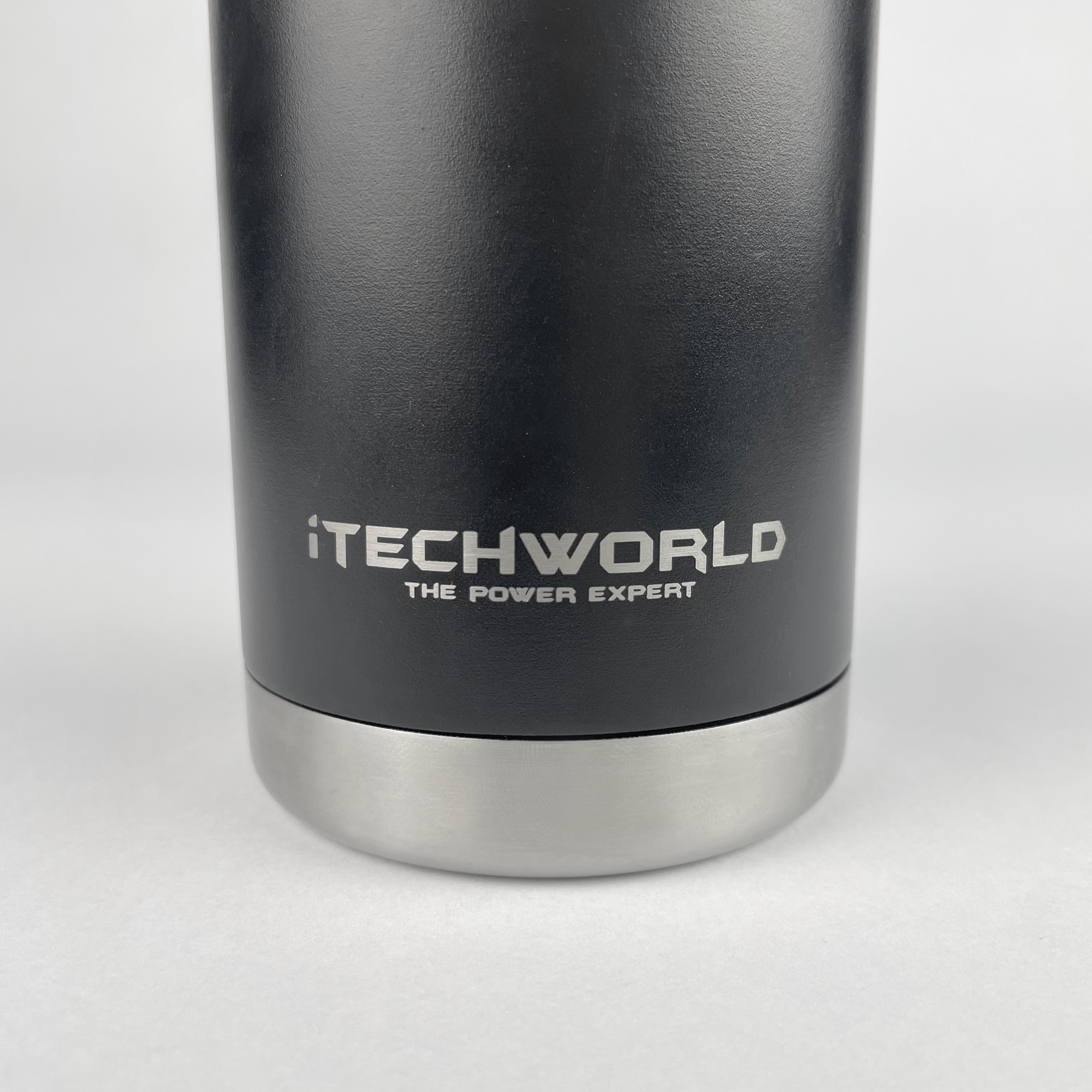 A close-up of a black iTechworld 375mL Can Cooler made of insulated stainless steel with a metal base. "iTECHWORLD THE POWER EXPERT" is printed in white on the cooler.