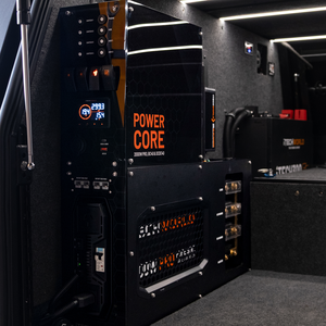A close-up of the iTechworld | Power Core | All-in-One Complete System, showing its digital displays, switches, wiring, and integrated 2000W inverter inside a vehicle compartment lit by LED strip lighting.