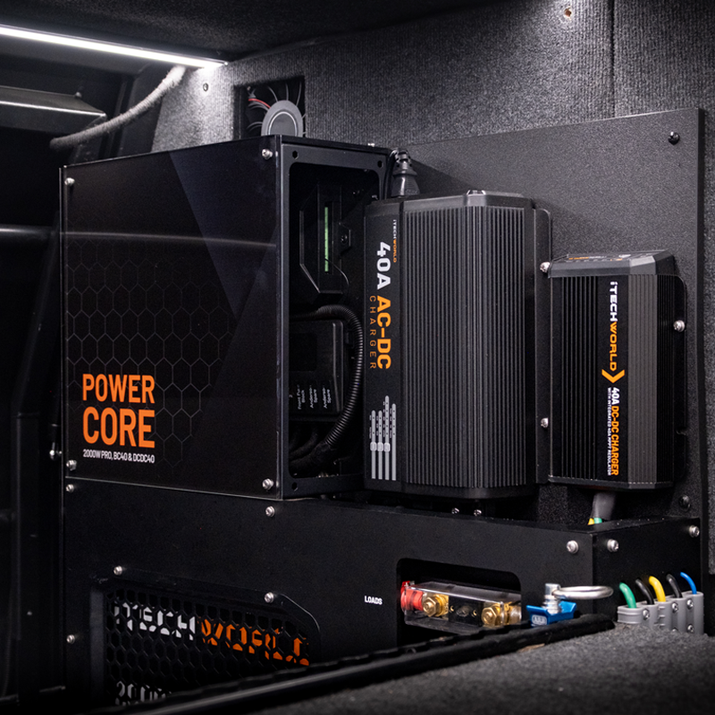 A close-up of the iTechworld Power Core All-in-One Complete System shows its 12V power setup, connected electronic components, switches, and wiring inside a carpet-lined compartment.