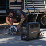 A person is using a circular saw outdoors, powered by the iTechworld 3600W 300Ah PS3600 PRO Portable Lithium Power Station, with a truck visible in the background. Equipped with safety glasses and earmuffs, they demonstrate how this dependable off-grid power solution—featuring a robust LiFePO4 lithium battery—makes outdoor projects both easy and safe.