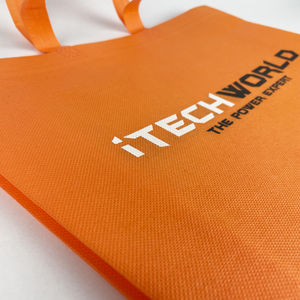 Close-up of an orange iTechworld Reusable Tote Bag featuring "iTECHWORLD THE POWER EXPERT" in white and black. This sturdy gear bag has two handles and rests on a white surface.