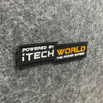 A rectangular iTechworld Velcro Patch displays the text: POWERED BY iTECH WORLD THE POWER EXPERT on gray fabric. The words “iTECH” and “WORLD” stand out in white and orange, forming a bold Power Expert logo embroidered by the iTechworld brand.