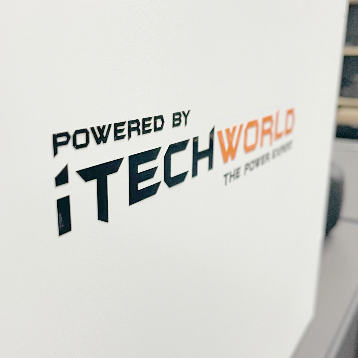 Close-up of the iTechworld | Sticker | S/M/L by iTechworld, showing "POWERED BY iTECHWORLD THE POWER EXPERT" in black and orange on a durable vinyl surface.